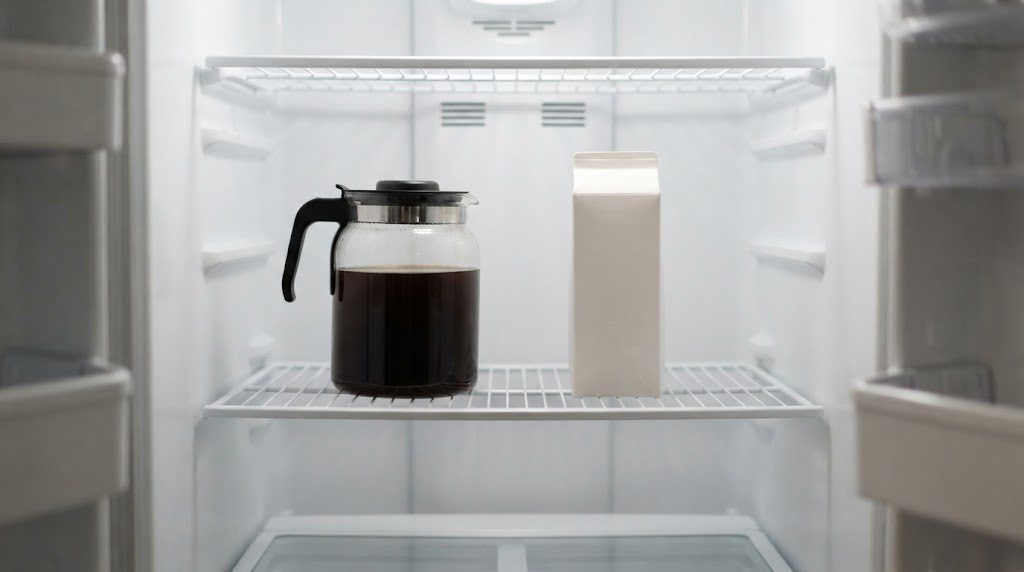 冷蔵庫の棚に、水出しコーヒーが入ったフタ付きのガラスのピッチャーと白い牛乳パックが置かれている様子